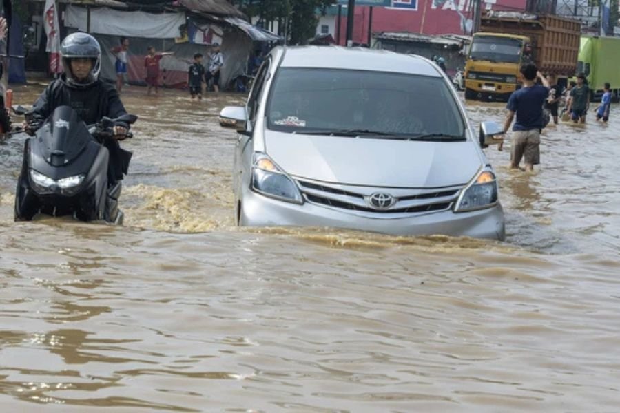 Pengendara motor dan mobil berusaha melintasi banjir di Dayeuhkolot, Kabupaten Bandung, Jawa Barat, Jumat (22/11/2024).